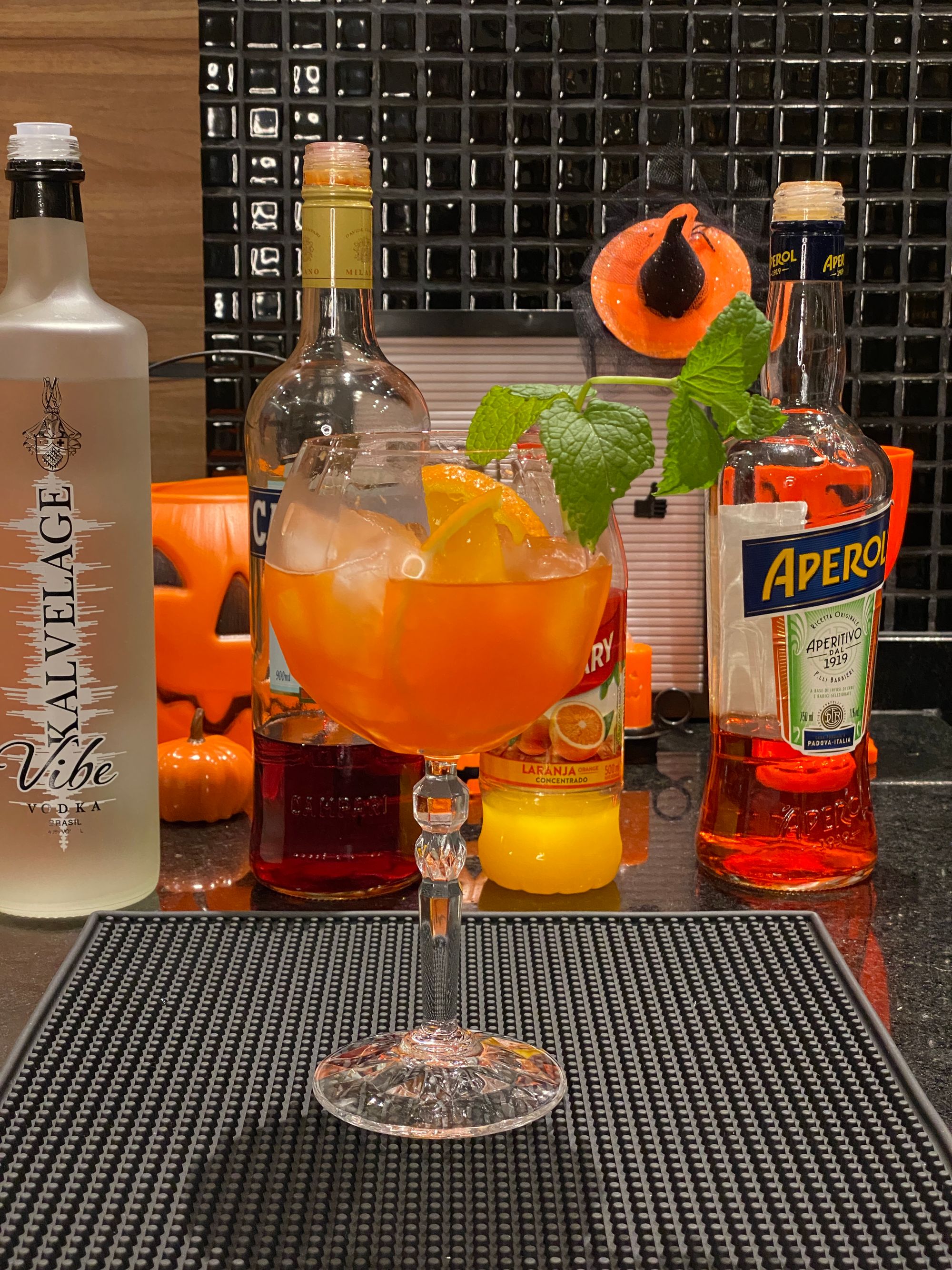 Drink de Halloween à frente das garrafas de vodka Kalvelage, Campari, Aperol e suco Maguary de laranja