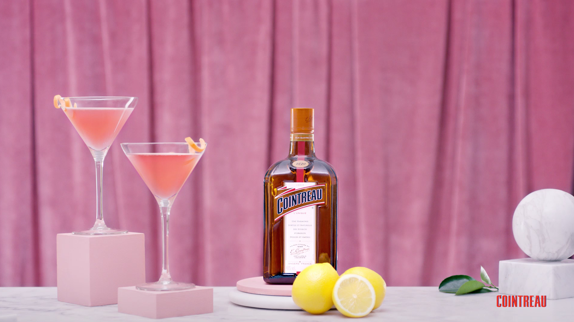 Duas taças do drink Cosmopolitan, garrafa de licor Cointreau e limões sicilianos que fazem parte da receita do Cosmo