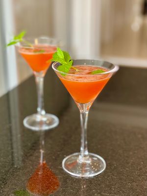 Duas taças Martini com drink autoral de Aperol e Vodka, com garnish de hortelã