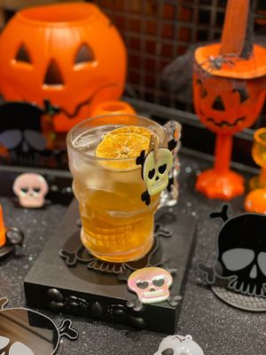 Drink de Halloween cor de abóbora com decoração de caveiras e abóboras