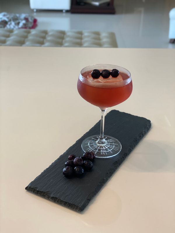 Drink com gin rosé, aguardente de uva e mirtilos